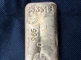 un lingot d'argent portant un poinçon, posé sur un tissu bleu
