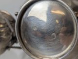 a close up of a silver tea pot with a bird on it