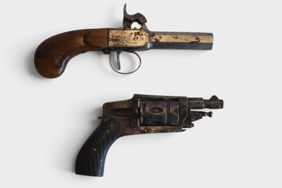 pair of old guns on a white surface with a white background