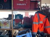 un homme vêtu d'une veste orange, debout devant une étagère remplie d'outils
