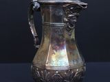 a silver coffee pot on a table with a black background