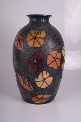 un vase noir orné de fleurs peintes sur un fond blanc