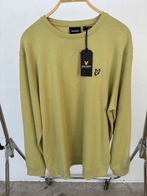 un pull vert suspendu à un cintre, avec une étiquette dessus
