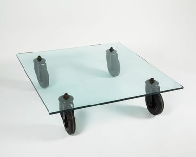 a glass table with wheels on it on a white surface