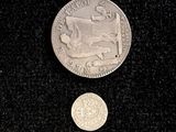 a silver coin sitting next to a silver coin on a black surface