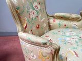 a chair with a floral upholstered seat on a red carpet