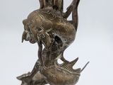 bronze statue of a mermaid with a fish head on a pedestal