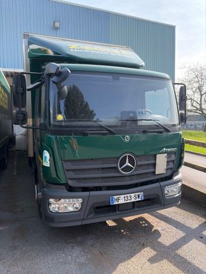 un grand camion vert garé devant un immeuble