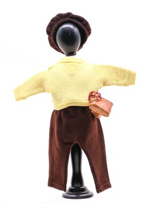 une poupée qui porte un pull jaune et un pantalon marron