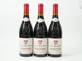 trois bouteilles de vin rouge posées l'une à côté de l'autre sur une surface blanche