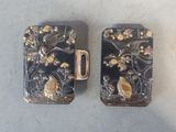 une paire d'étuis à cigarettes noirs et dorés ornés d'oiseaux et de fleurs