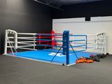 a boxing ring in the middle of a room with boxing gloves on the floor