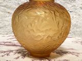 un vase en verre jaune posé sur une table recouverte d'une nappe violette et blanche