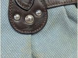 a blue bag with a brown leather strap on it