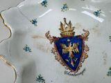 a blue and gold plate with a coat of arms and a crown on it