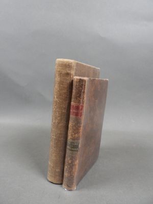 two old books sitting on top of each other on a table