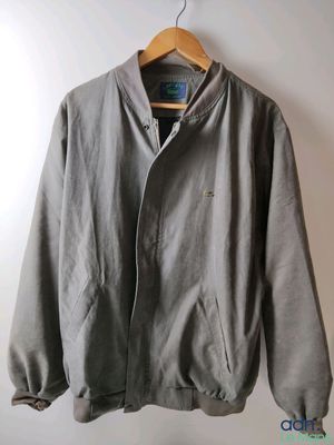 a grey jacket hanging on a hanger against a white wall