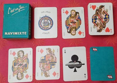 Des cartes à jouer sont disposées sur une table, à côté d'une boîte de cartes à jouer