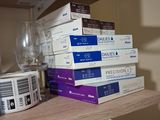 a stack of books sitting on a shelf next to a wine glass