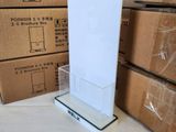 a white sign on a clear stand in front of a stack of boxes