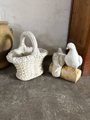 a white bird sitting next to a basket with a bird on it