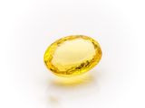 a yellow sapphire stone on a white surface