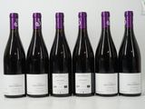 six bouteilles de vin sont alignées sur une surface blanche