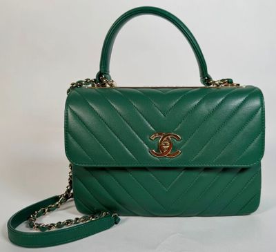 un sac à main vert muni d'une bandoulière en chaîne et d'un fermoir doré