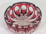 a red and white glass ashtray sitting on a white surface
