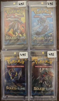 quatre cartes Pokémon sous blister posées sur une table