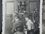 a black and white photo of a group of men standing outside of a train
