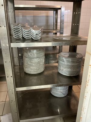 many plates and bowls on the shelves in the kitchen