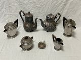 de nombreuses théières et tasses en argent posées sur une table