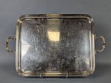 un plat ancien en argent avec des poignées, sur fond gris