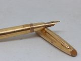 a gold pen sitting on top of a white table