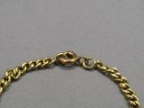 a close up of a gold chain bracelet on a gray surface