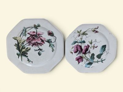 two plates with floral designs on them on a white surface