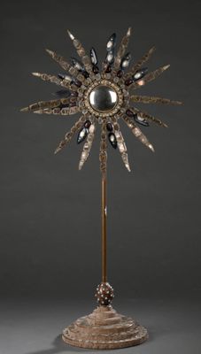 une sculpture en argent et en or représentant un tournesol, posée sur un socle en bois