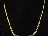 a gold and silver necklace on a black mannequin