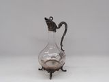 un pichet ancien en verre plaqué argent, posé sur un socle et muni d'une anse