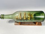 une bouteille en verre contenant un bateau, posée sur un socle en bois