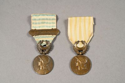 two medals with ribbons on them sitting on a gray surface