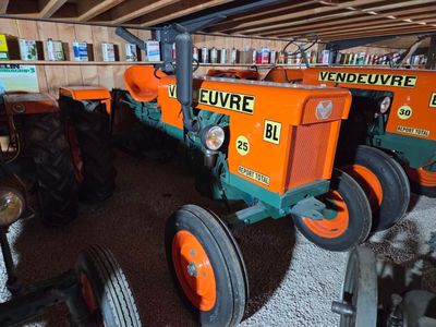 two orange and green tractors parked in a garage
