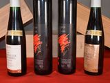 three bottles of wine sit on a red table cloth next to a wooden box