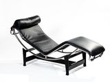 une chaise longue et un pouf en cuir noir sur fond blanc