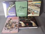 several books are sitting on a gray surface with a gun in the background