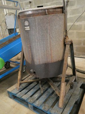 un grand chaudron en métal posé sur une palette en bois