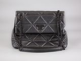 a black quilted purse with a chain strap on a white background