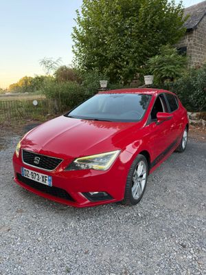 La voiture rouge est garée devant un bâtiment en pierre.