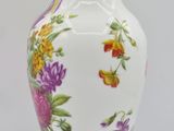 a white vase with colorful flowers on it on a white surface